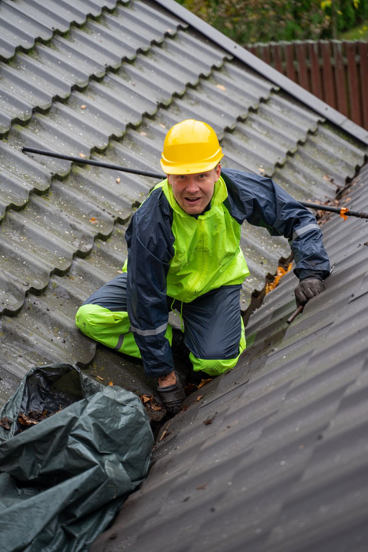 A roofer in a hard hat checking a pitched roof